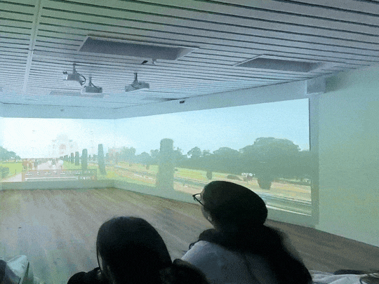 Students sit on the floor watching a wraparound projection of the Taj Mahal and its gardens
